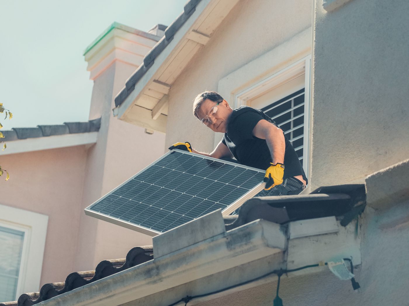 A technician handling a solar panel on a rooftop